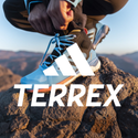 Adidas Terrex hiking shoe on rocky trail, person tying laces for outdoor adventure