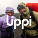 Hikers in waterproof Uppl jackets smiling on rainy trail, gear ready for outdoor adventure