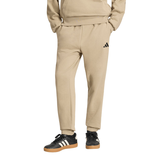 Pantalón de buzo Adidas Feelcozy en color beige.